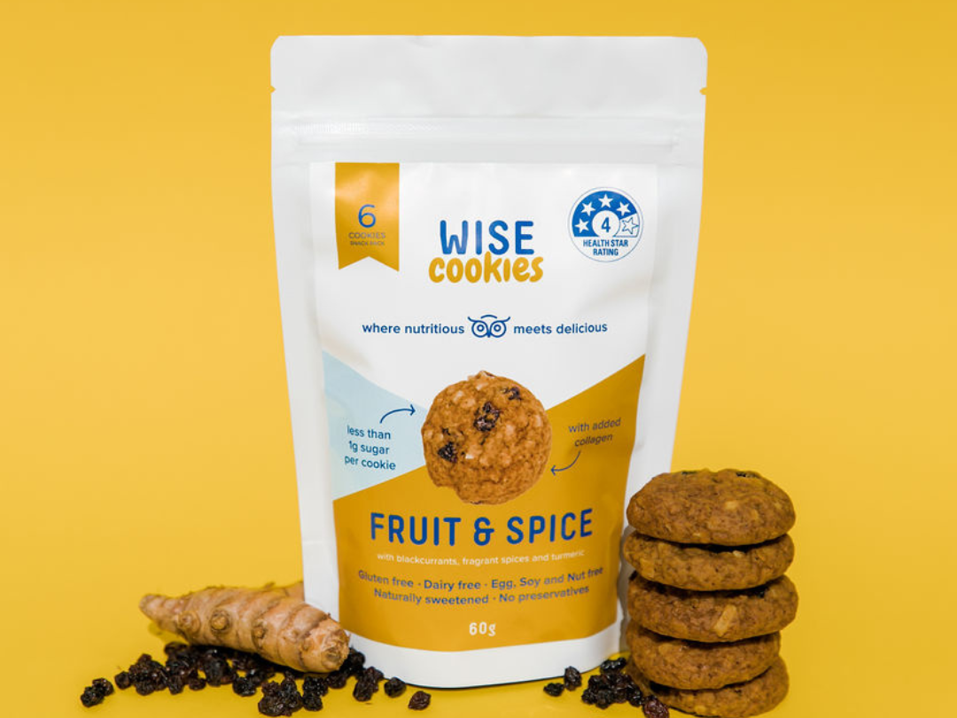 Wisefoods | A snack pack of 4.0 Health Star rated Fruit & Spice cookies with collagen, with fresh turmeric, dried blackcurrants and a stack of cookies alongside