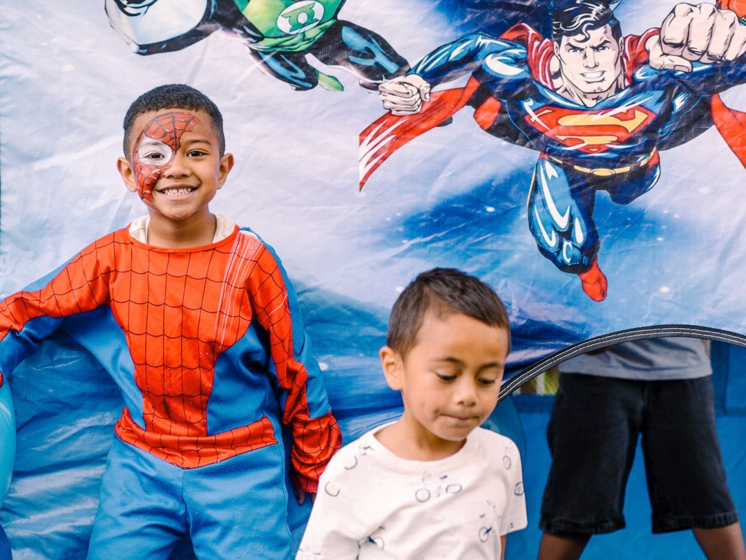 Wisefoods | Boy in a Spiderman suit with Superman picture in the background at a Kindness Collective Foundation event