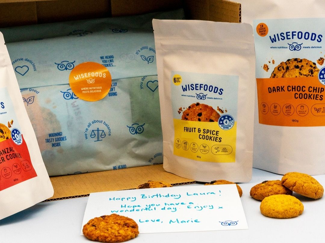 Wisefoods | Healthy cookie care pack gift wrapped in pale blue tissue, with 3 packs of cookies, loose cookies and a handwritten message