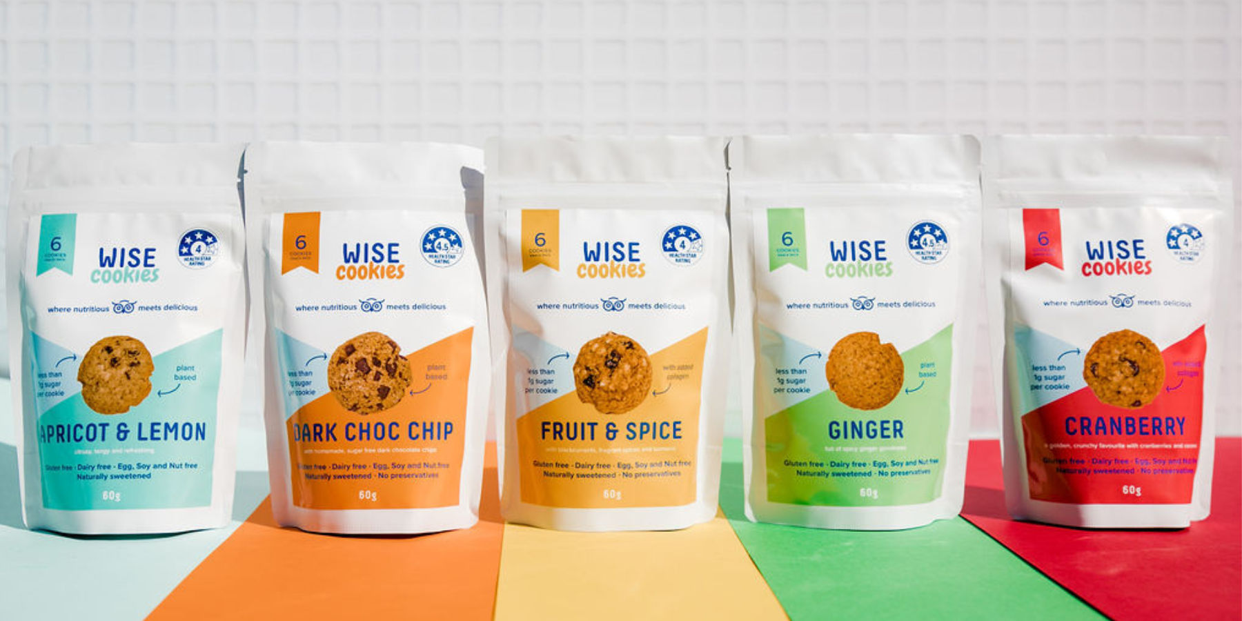 Wisefoods | Five flavours of Health Star rated, allergy-friendly 60g Wise Cookie Snack Packs lined up on a rainbow mat