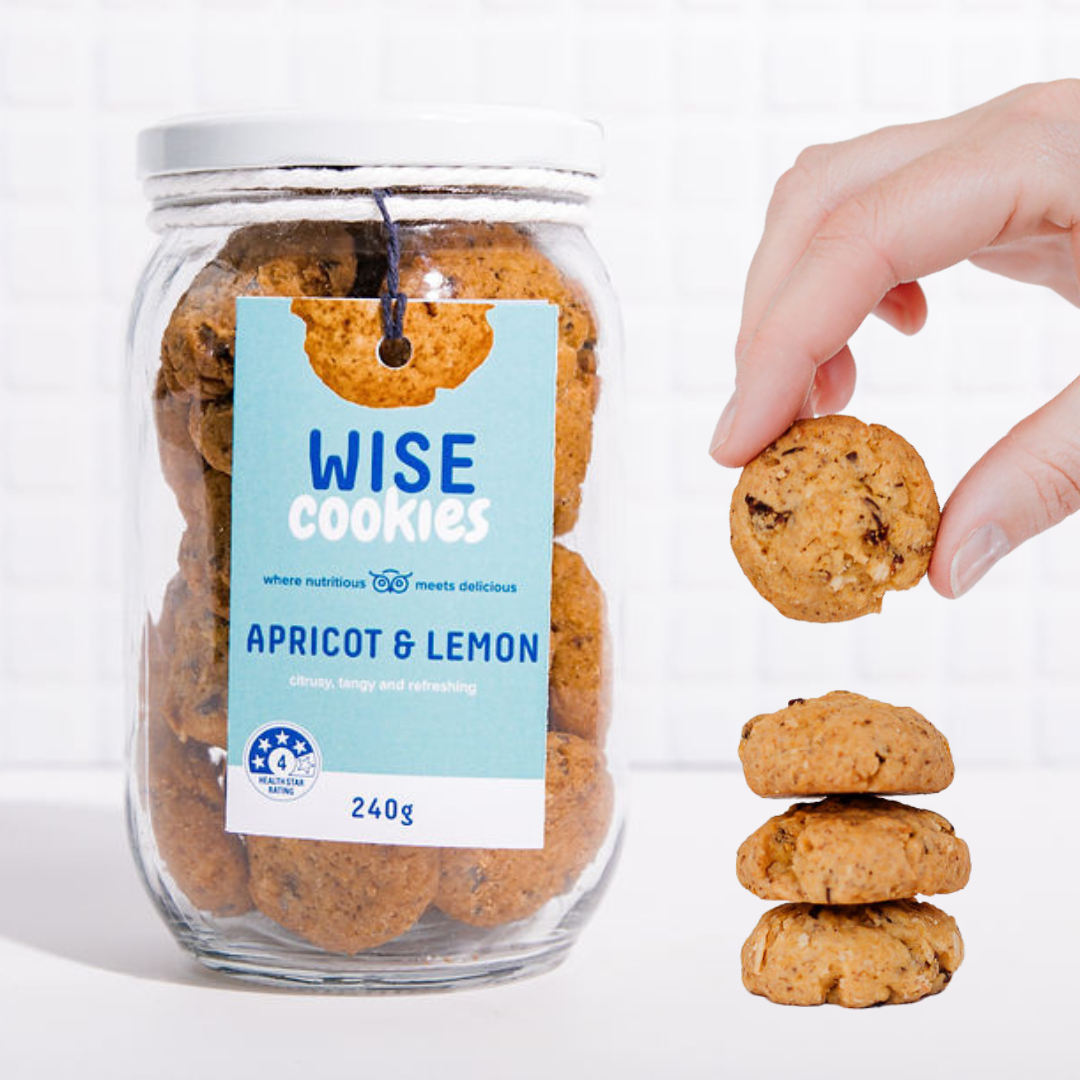 Wisefoods | 240g Glass Gift jar of 4.0 Health Star rated, allergy-friendly, plant based Apricot &amp; Lemon Wise Cookies with a stack of cookies on the right and a hand holding one cookie between thumb and forefinger above that