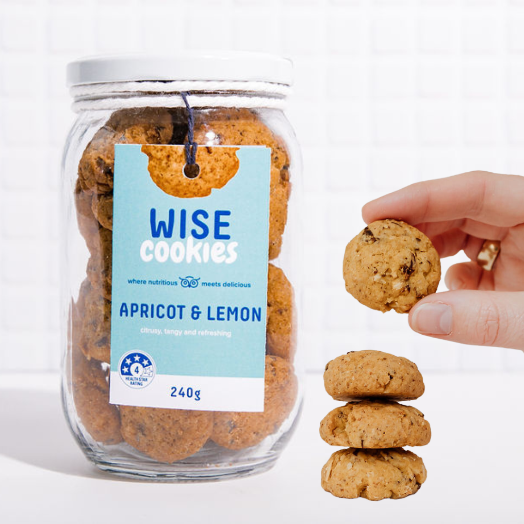 Wisefoods | 240g Glass Gift jar of 4.0 Health Star rated, allergy-friendly, plant based Apricot &amp; Lemon Wise Cookies with a stack of cookies on the side and a hand holding one cookie between thumb and forefinger