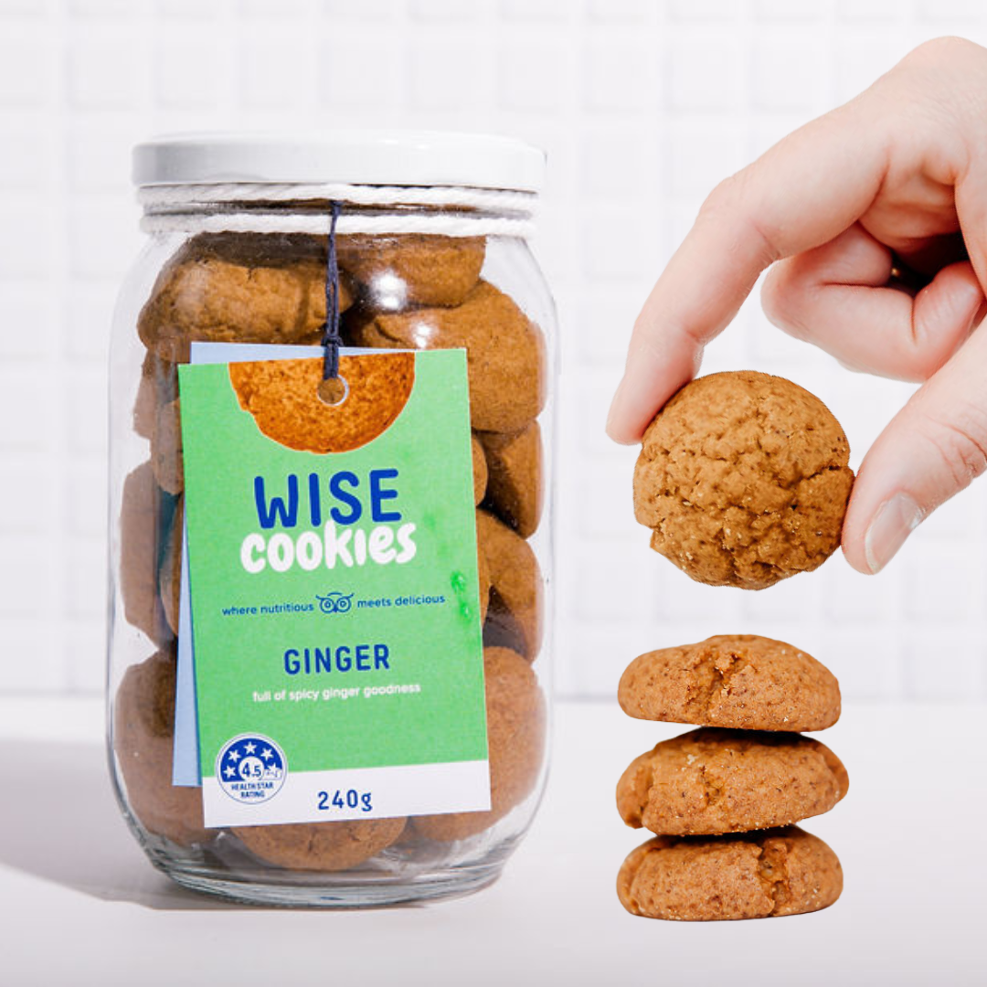 Wisefoods | 4.5 Health Star rated, allergy-friendly, low sugar Ginger Wise Cookies in a glass jar with a stack of loose cookies and a hand holding one between thumb and forefinger to the right of the jar