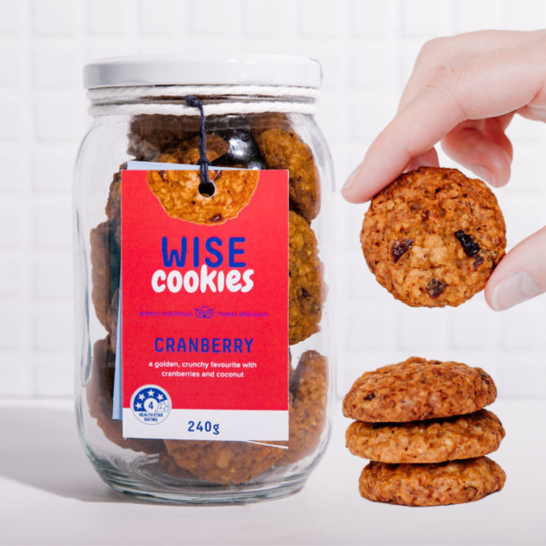 Wisefoods | 240g Glass Gift jar of 4.0 Health Star rated, allergy-friendly, collagen Cranberry Wise Cookies with a stack of cookies on the right and a hand holding one cookie between thumb and forefinger above that
