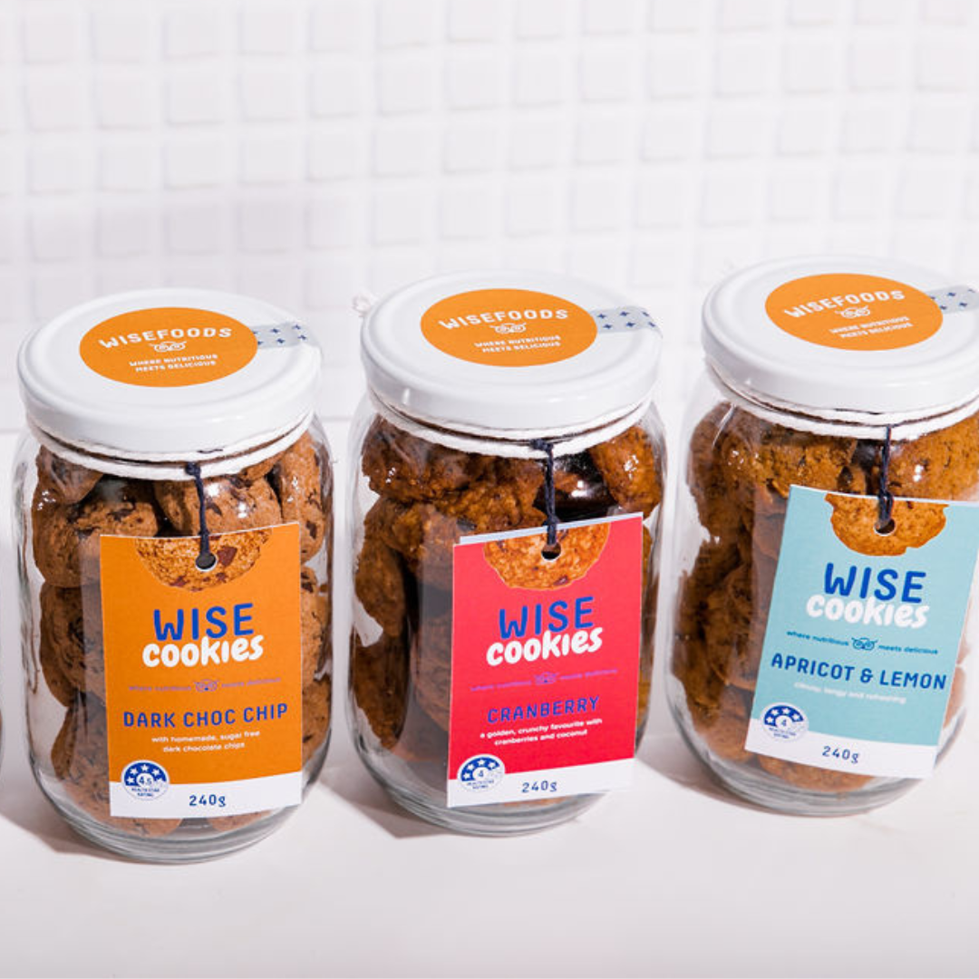 Wisefoods | A row of three 240g glass Gift jars of 4.0 &amp; 4.5  Health Star rated, allergy-friendly, low sugar Wise Cookies - from left to right, Dark Choc Chip, Cranberry and Apricot &amp; Lemon