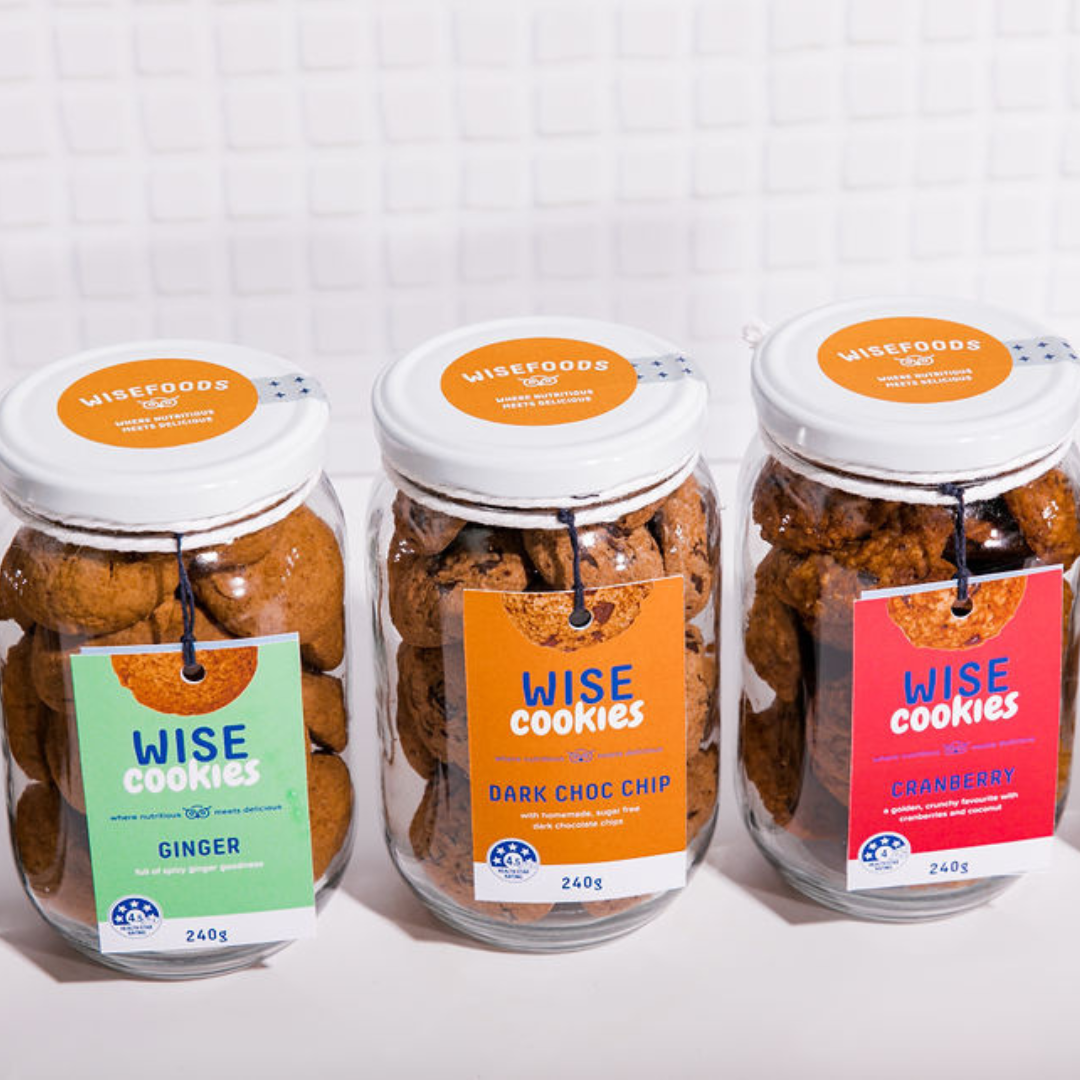 Wisefoods | A row of three 240g glass Gift jars of 4.0 &amp; 4.5  Health Star rated, allergy-friendly, low sugar Wise Cookies - from left to right, Ginger, Dark Choc Chip and Cranberry