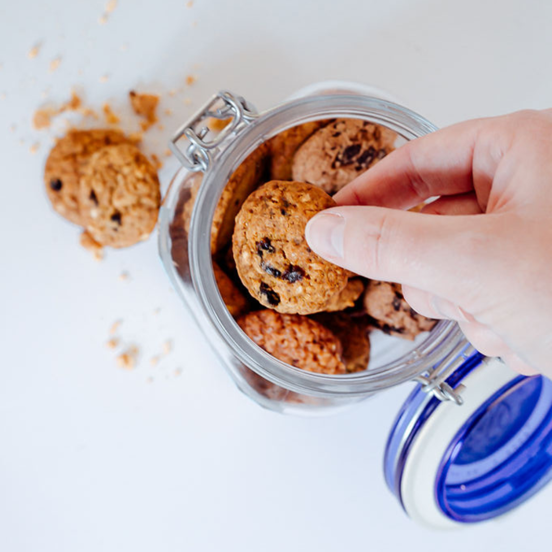 Wisefoods | Hand reaching into a jar, viewed from above, holding a 4.0 Health Star rated, allergy friendly, Fruit &amp; Spice Collagen Cookie