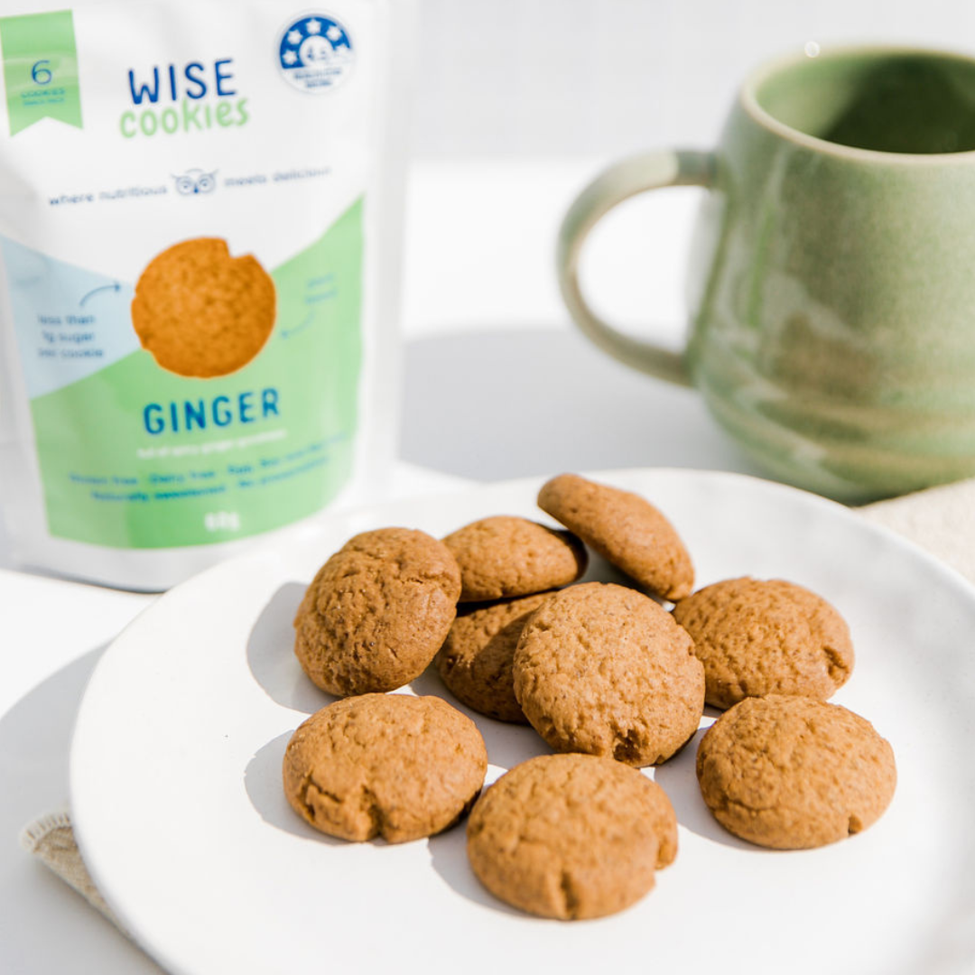 Wisefoods | 4.5 Health Star rated, allergy friendly, plant based Ginger Cookies on a white plate with a soft green mug and a Snack Pack in the background